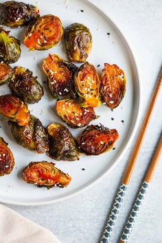 roasted brussel sprouts on a white plate with chopsticks next to them