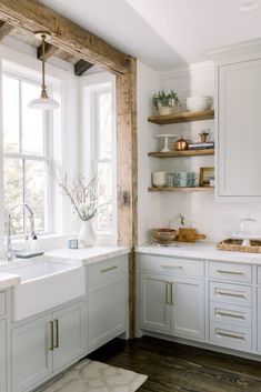 a white kitchen with open shelving and wooden shelves on the wall above the sink