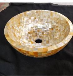 a bowl shaped sink made out of mother of pearl mosaic tiles on a black cloth