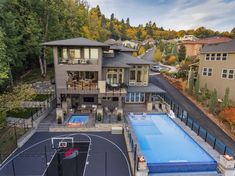 an aerial view of a house with a basketball court in the yard and a large swimming pool