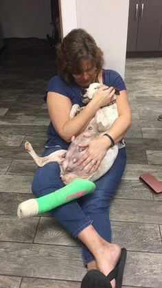 a woman sitting on the floor holding a cat