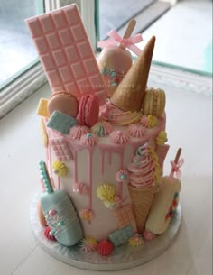 a cake decorated with ice cream, cookies, and candy on a table next to a window