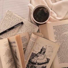 an open book sitting on top of a pile of books next to a cup of coffee