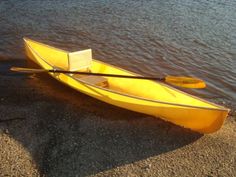 a yellow canoe sitting on top of a sandy beach next to the water's edge