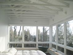 a bed sitting in a bedroom next to a window filled with lots of white furniture