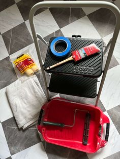 a black and white checkered floor with a red chair, paintbrushes and other items on it