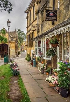 an old building with flowers in the front and on the side walk next to it