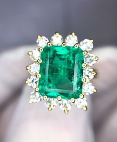 An Awe Inspiring 4 carat natural Colombian-origin rectangular emerald-cut emerald with a huge face that looks like a 5 carat (11.41mm x 9.53mm x 5.55mm measurements) is the feature of this 18k emerald diamond halo statement ring.  Fourteen (2.75mm) 0.80 carat diamonds; 1.12 carat total diamond weight of white-facing (H-I color) clean (VS and SI clarity), bright stones for a beautiful halo accent. Measurements of the face of the ring are 18.37mm x 16.35mm across. Width of the shank is 2.75mm at t Luxury Emerald Cut Rings Of Aaa Quality, Luxury Emerald Cut Rings With Aaa Quality, Luxury Emerald Cut Aaa Quality Rings, Elegant Rectangular Emerald Ring Gia Certified, Elegant Rectangular Gia Certified Emerald Ring, Gia Certified Rectangular Emerald Ring, Elegant Gia Certified Rectangular Emerald Ring, Gia Certified Luxury Square Cut Emerald Ring, Luxury Gia Certified Square Cut Emerald Ring