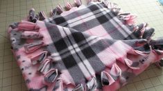 a pink and black plaid blanket laying on top of a cutting board