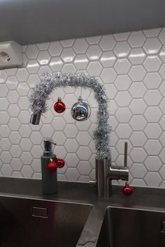 a kitchen sink with christmas decorations hanging from it's faucet and chrome faucets