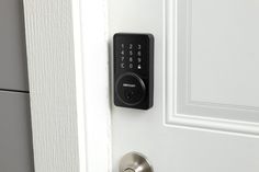 an electronic door lock on a white door with black keys and numbers in the keypad