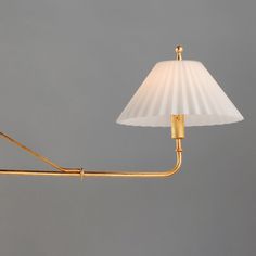 a lamp that is on top of a table next to a gray wall with a white shade