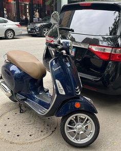 a blue scooter parked next to a black car