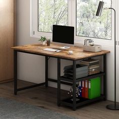 a desk with a computer on top of it next to a window and bookshelf