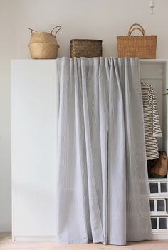 the curtains are open in this room with white walls and flooring, along with baskets on top of shelves