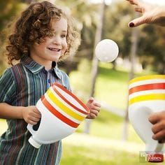 a little boy is juggling something in his cup