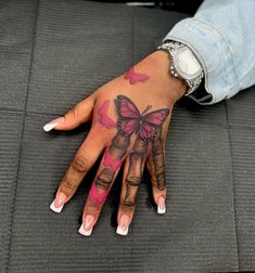 a woman's hand with pink and black tattoos on her left palm, which has a butterfly painted on it