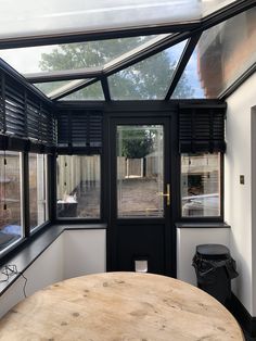 an enclosed patio area with a wooden table and black shutters