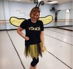 a woman in a black shirt and yellow skirt with a bee costume on her head