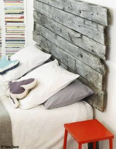 a bed with white sheets and pillows next to a wooden headboard made out of wood planks