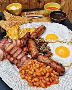 a white plate topped with bacon, eggs and beans