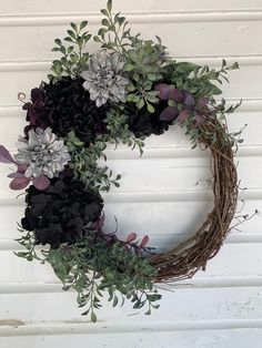 a wreath with flowers and greenery hanging on a wall