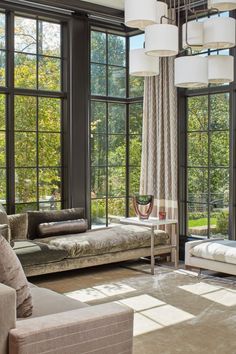 a living room filled with lots of windows next to a couch and two chaise lounges