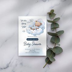 a baby shower card with a teddy bear in the clouds on it and eucalyptus leaves