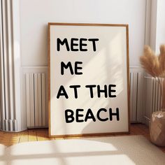 a sign that says meet me at the beach next to a vase with dry grass