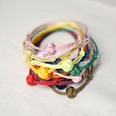 a bunch of bracelets are stacked on top of each other with different colored cords