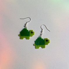 a pair of earrings with green plastic animals on them