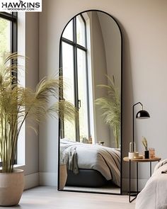 a large mirror sitting next to a bed in a bedroom