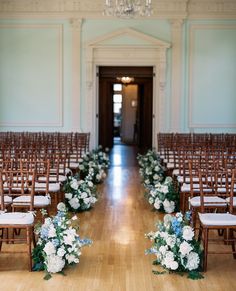 rows of chairs with white and blue flowers on them in front of an entrance way