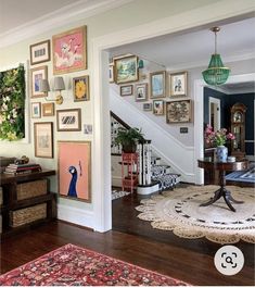 a living room filled with lots of pictures on the wall next to a stair case