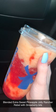 a hand holding a cup with red and blue liquid in it, on the inside of a car