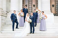 a bride and groom with their bridal party in front of the doors of a building