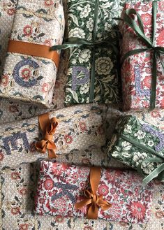 several wrapped presents with bows on them sitting on a table cloth covered in floral fabric