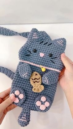 a crocheted cat purse being held up by someone's hand and holding it