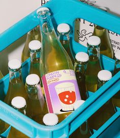 several bottles of soda in a blue crate with labels on the side and one is empty