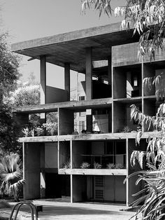 black and white photograph of an apartment building with plants on the balconies in front