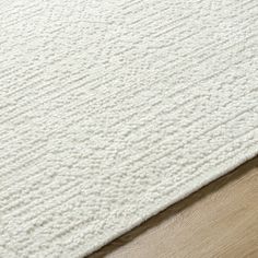 a white rug on top of a wooden floor next to a door handle and drawer