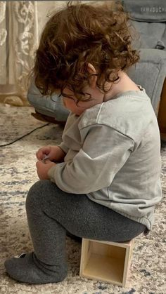 a small child sitting on top of a wooden box