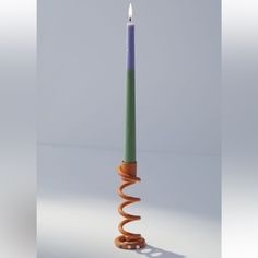 a purple and green candle sitting on top of a white table next to an orange spiral