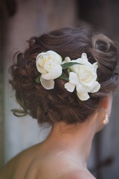 the back of a woman's head with white flowers in her hair, looking down