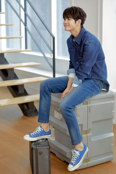 a young man sitting on top of a suitcase