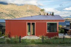 a red house with two people standing on the roof and one person sitting at the door