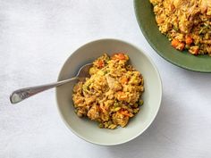 two bowls filled with rice and meat on top of a white tablecloth next to each other