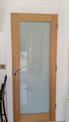 a wooden door with frosted glass on the front and side doors, in a white room