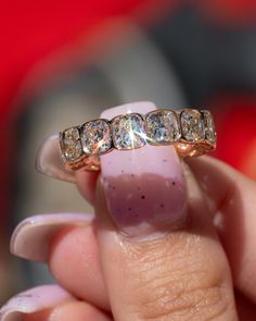 a woman's hand holding a gold ring with three diamonds on top of it