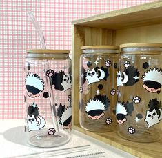 three glass mugs sitting on top of a wooden shelf next to a straw holder